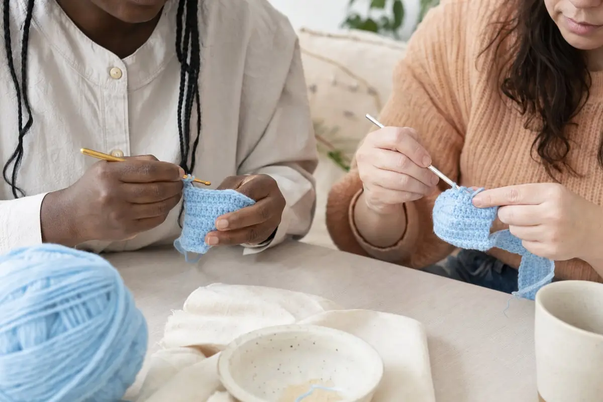 Two people hold crochet hooks in the pencil grip and the knife grip