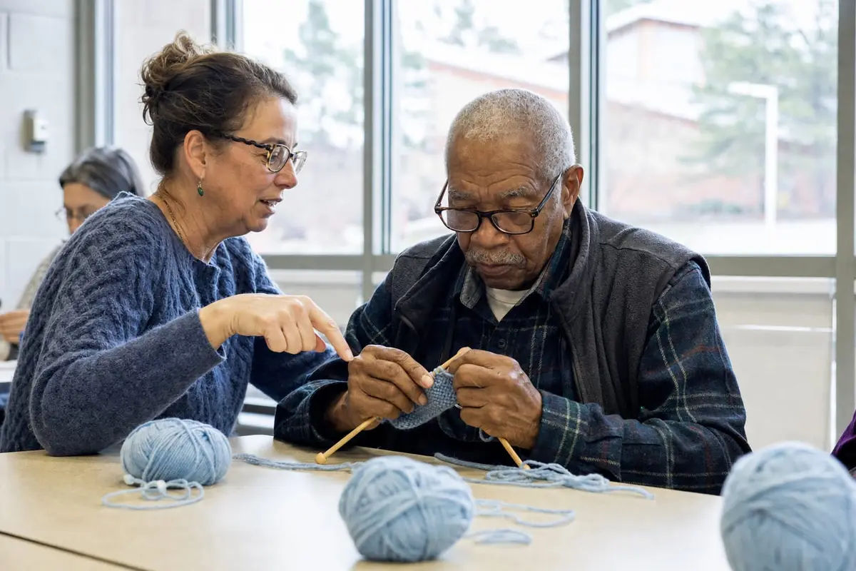 An older man knits his first garter stitch rows at a community center class