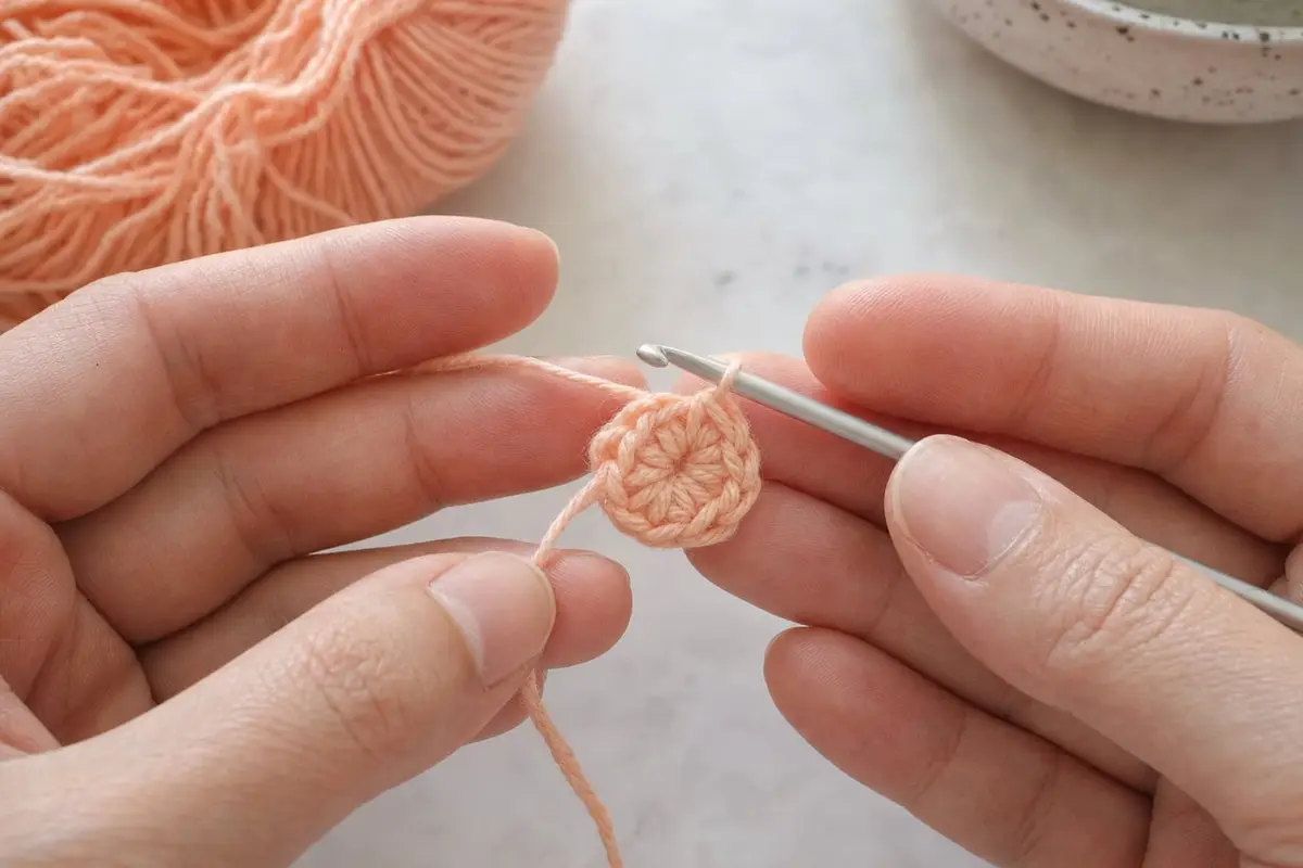 Fingers pull the tail to close a crochet magic ring with six stitches